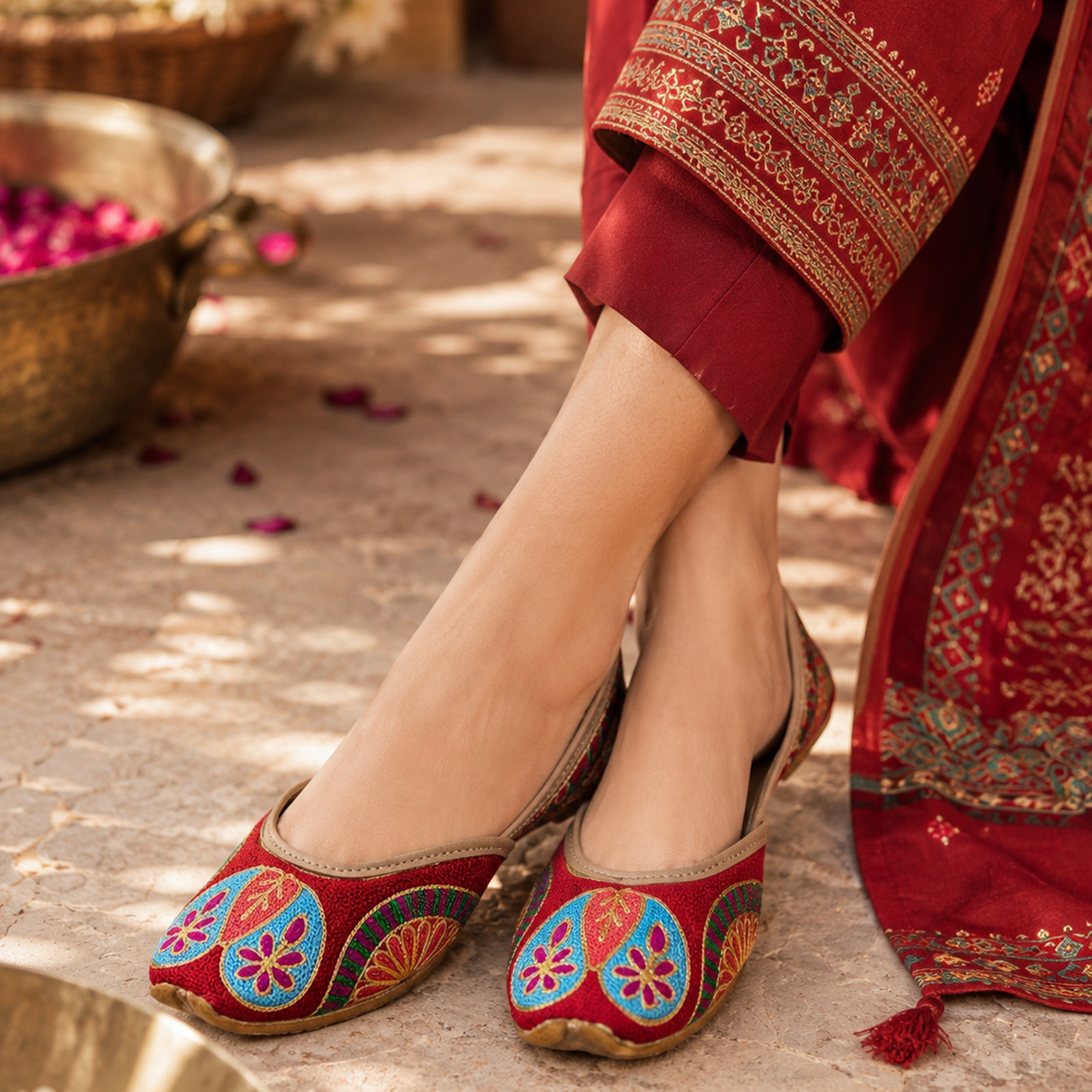Red embroidered shoes with traditional patterns worn by a person in a red outfit.
